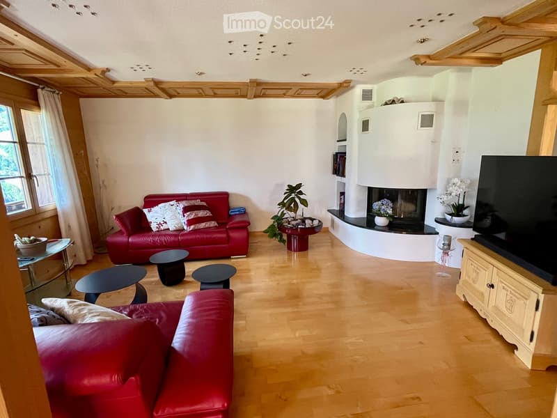 Modern living room with wooden flooring, red leather sofa, fireplace, coffee table, and television.