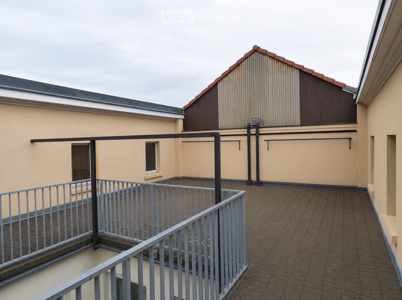 Balcony with metal railing, tiled floor, and a small window on the adjacent building.