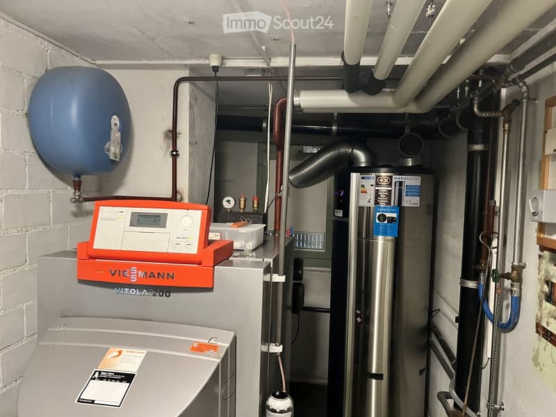 Utility room with water tank, thermostat, boiler, and various pipes.