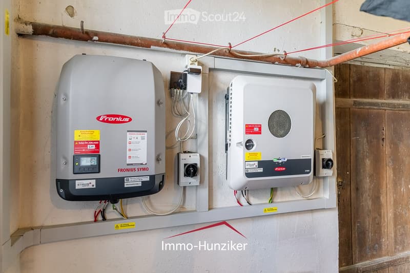Two solar inverters mounted on a wall with visible wiring and control panels.