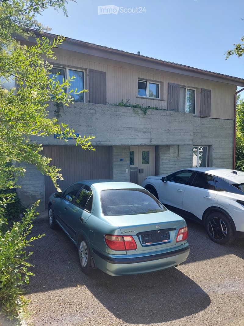 Two-story house with a garage and parking area for two cars.
