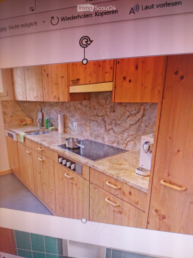 A modern kitchen with wooden cabinets, a stove, and a sink, displayed on a computer screen.