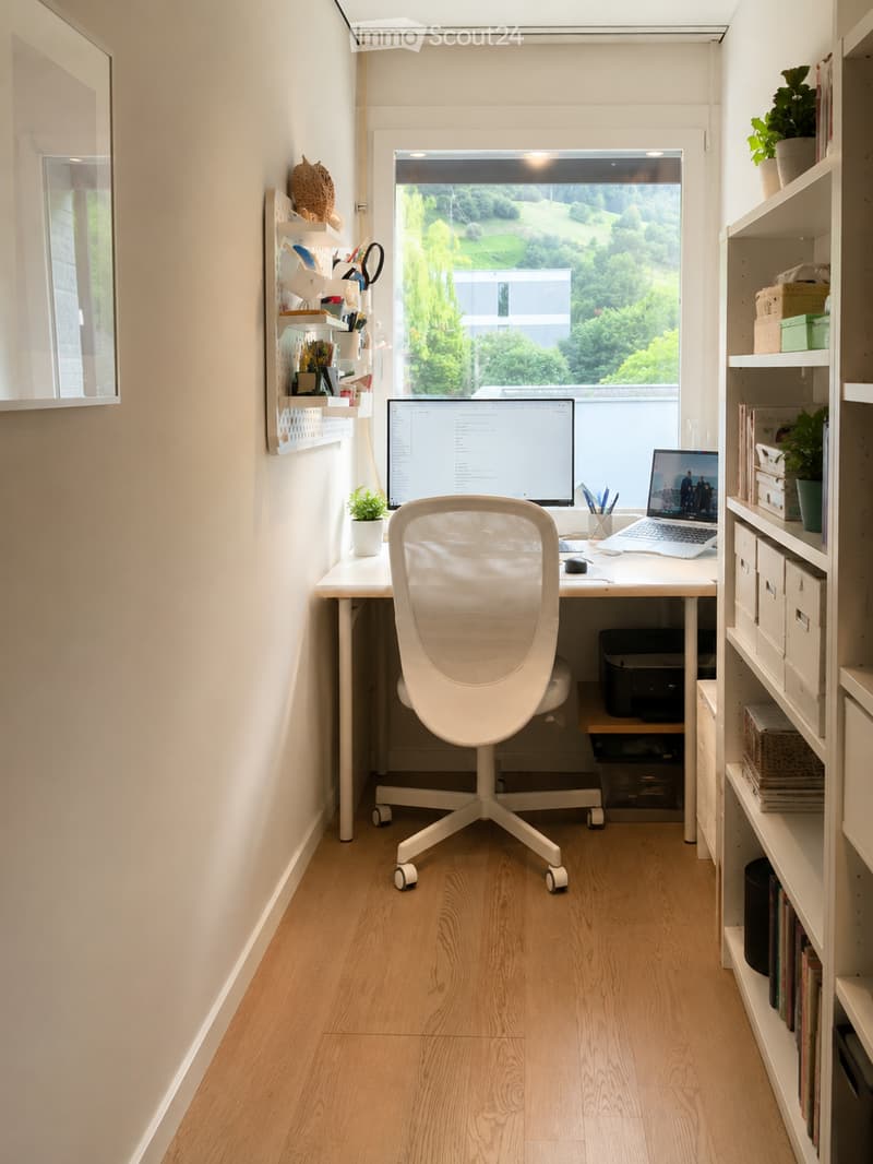 A modern, well-lit home office with a white ergonomic chair, a wooden desk, a laptop, a large screen, and shelves with books and plants. The room has light wooden flooring and large windows offering a scenic view.