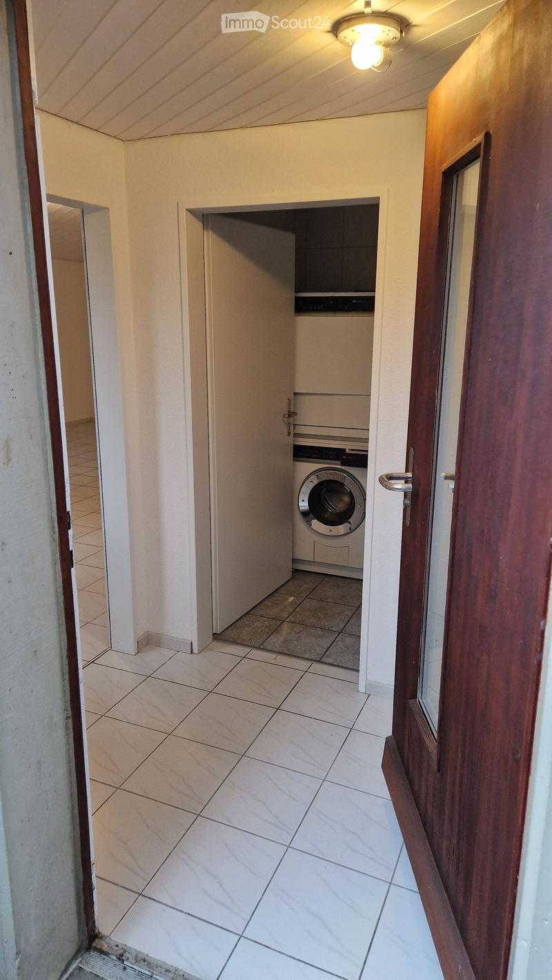 Small room with washing machine and door to another room