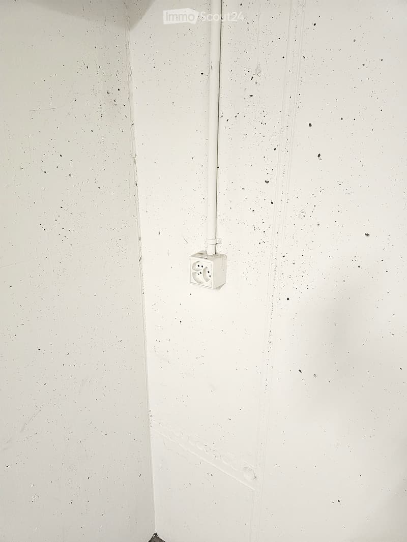 Empty room with bare walls and a single electrical outlet visible on the wall.