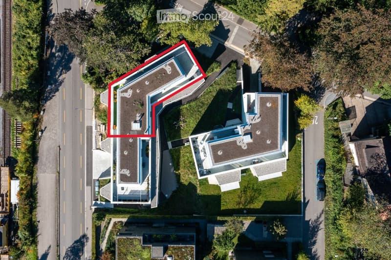 Aerial view of a multi-story residential building with a modern design, featuring a flat roof and multiple sections connected by walkways.