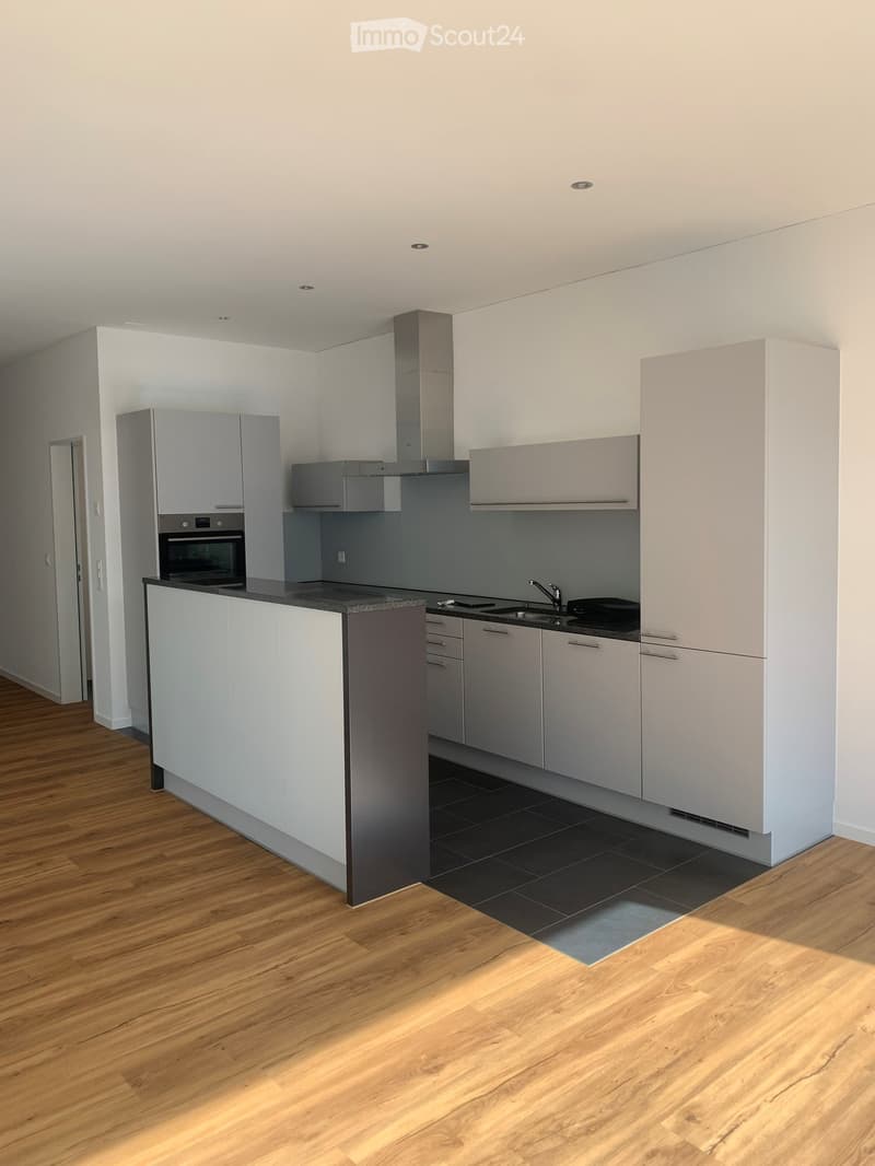 Modern kitchen with white cabinets, a central island, and a black countertop. Features include an oven, sink, and faucet.