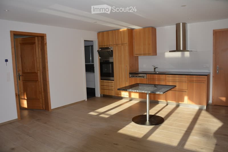 Modern kitchen with wooden cabinets, granite countertop, built-in oven, sink, and a round table with a metal base.