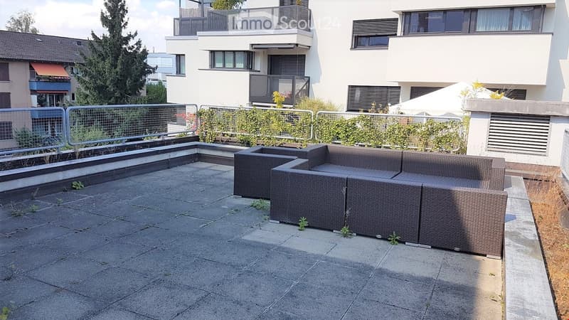 Outdoor terrace with wicker sofa, metal railings, and plants