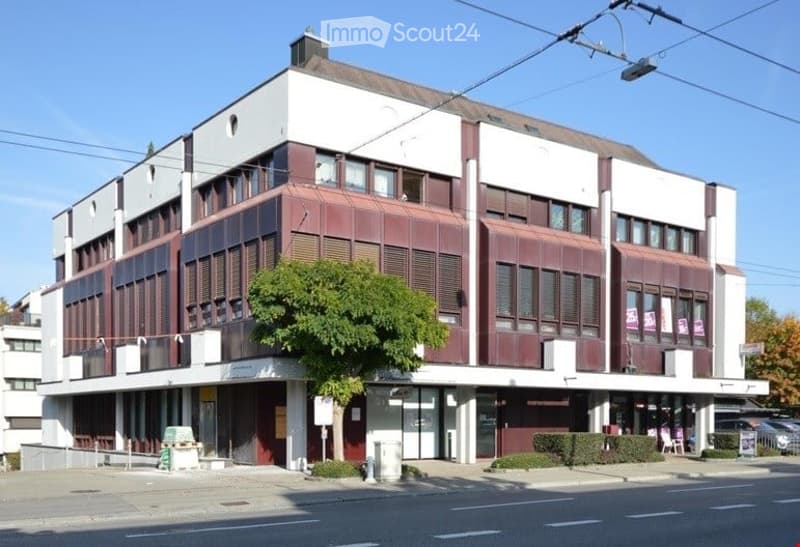 3 story building, red and white exterior, multiple windows, tree in front, cars parked on the side