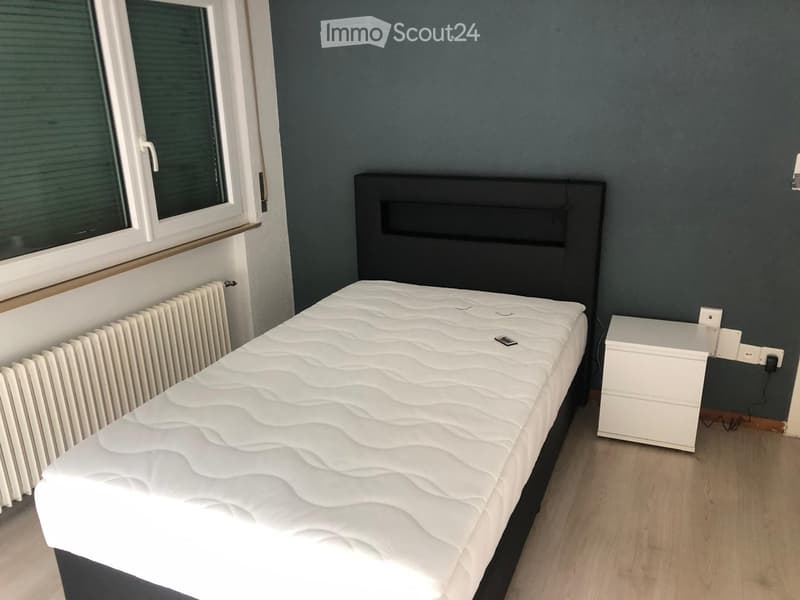 Single bed, white mattress, bedside table, radiator, wall plug