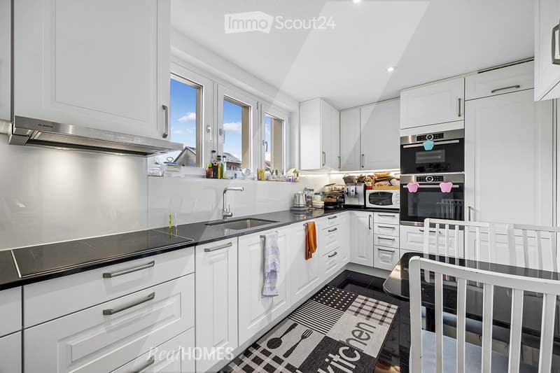 modern kitchen, white cabinets, black countertops, stainless steel appliances, large windows