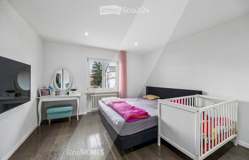 Bedroom with bed, crib, desk, mirror, TV, radiator, wooden floor