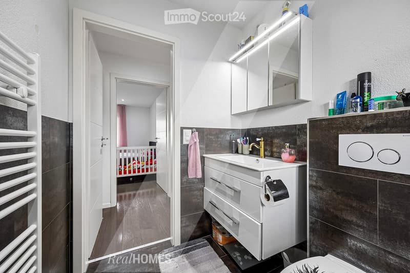 modern bathroom with white tiles, white vanity, mirror, sink, and toilet