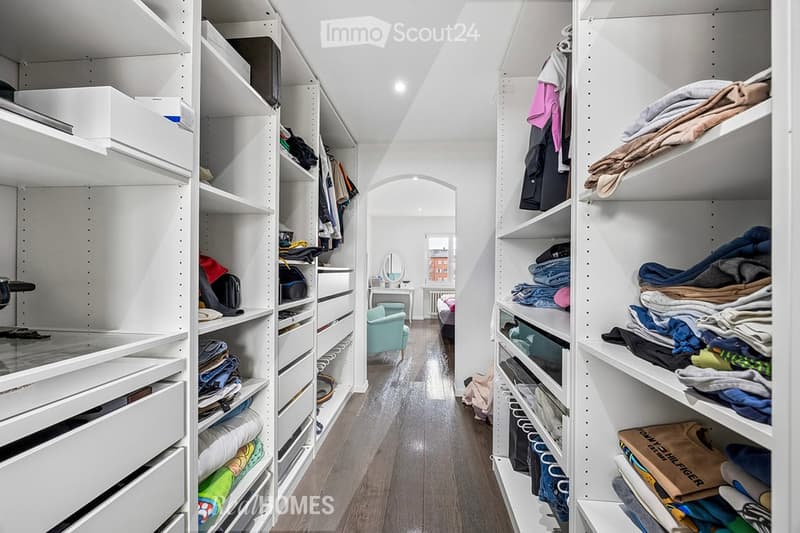 walkway between two wardrobes, wooden floor, white shelves, clothes, bags, boxes