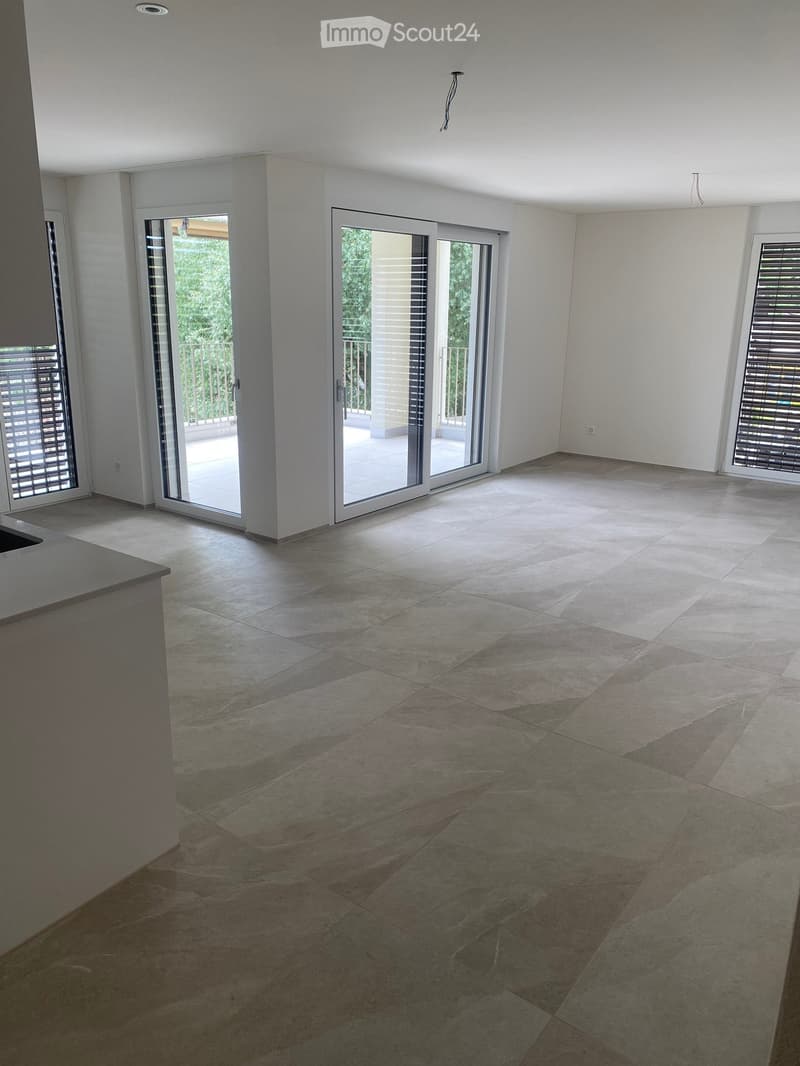 Empty room with large sliding glass doors leading to a balcony, tiled floor, and white walls.