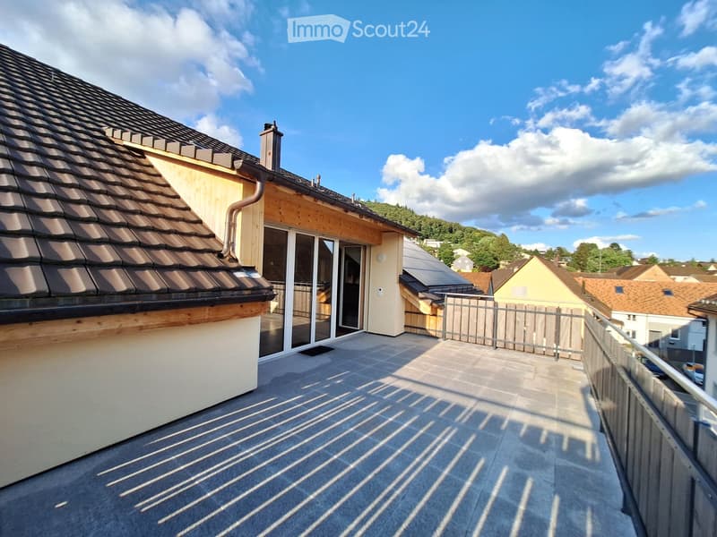 Roof terrace with concrete tiles, metal railing, and sliding glass doors leading to the building.