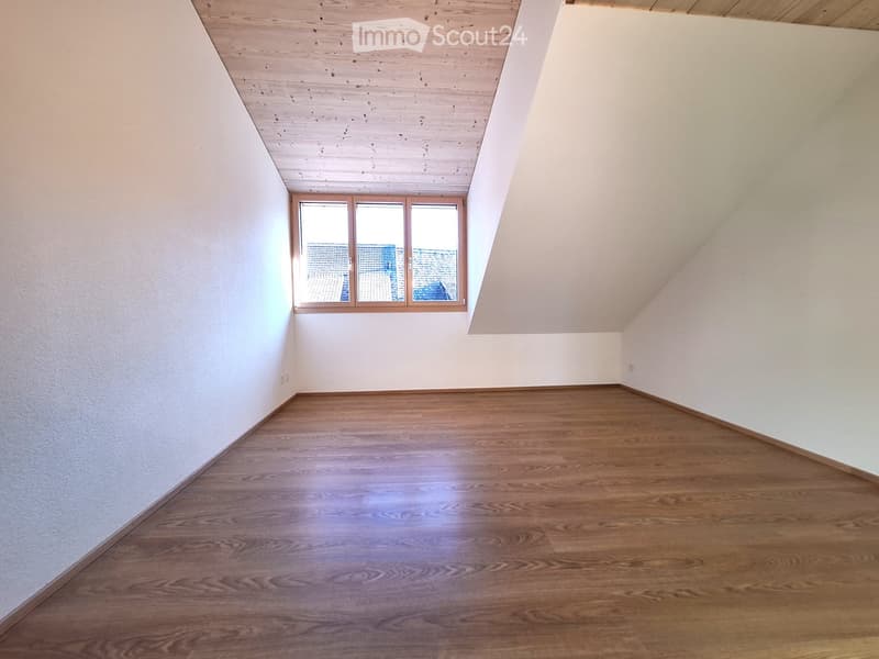 Empty room with wooden flooring, white walls, and a single window with wooden frame letting in natural light.