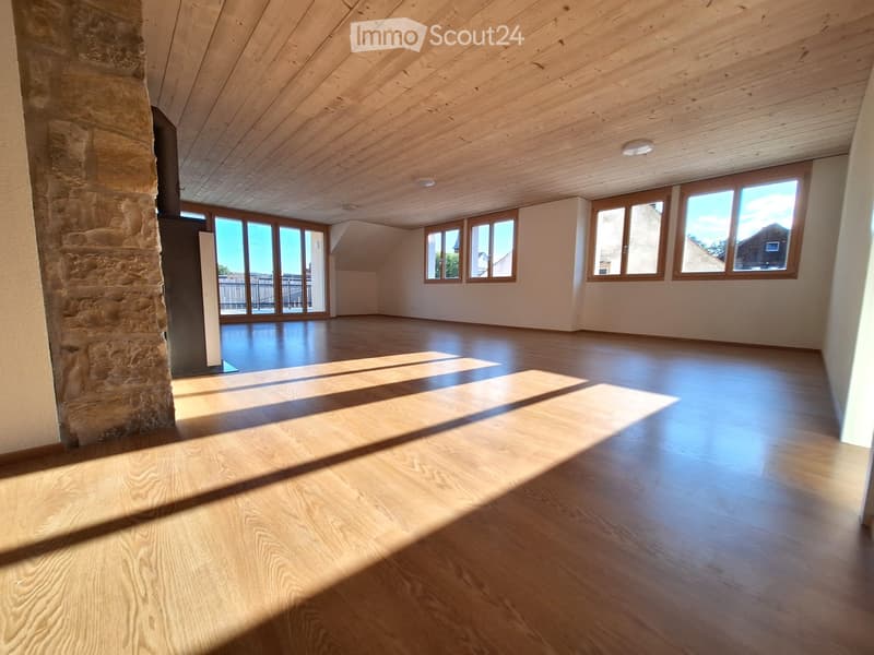 Empty room with wooden flooring, large windows, and a stone pillar. No furniture or equipment present.