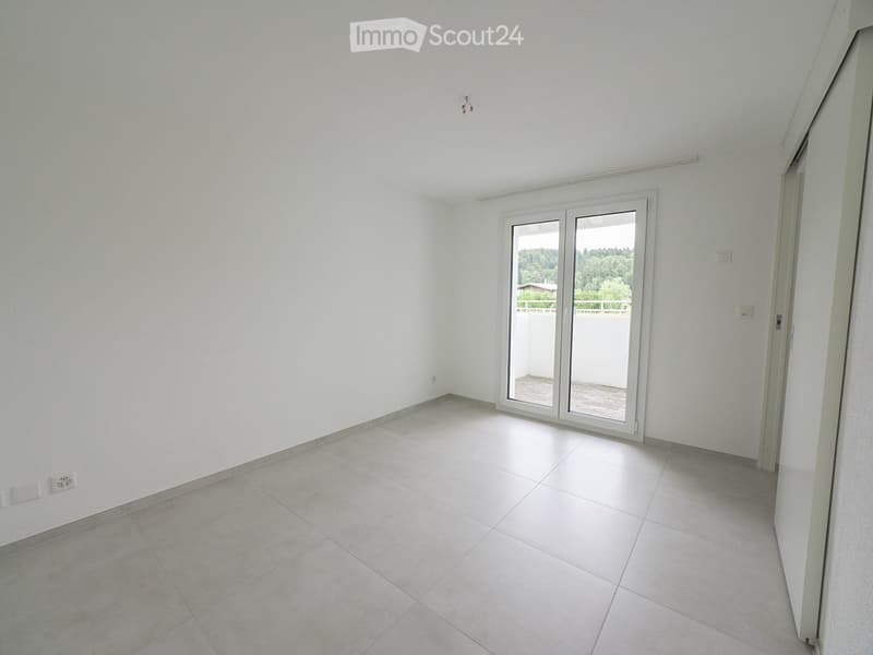 Empty room with white tiled floor and white walls, featuring a large sliding glass door leading to a balcony.