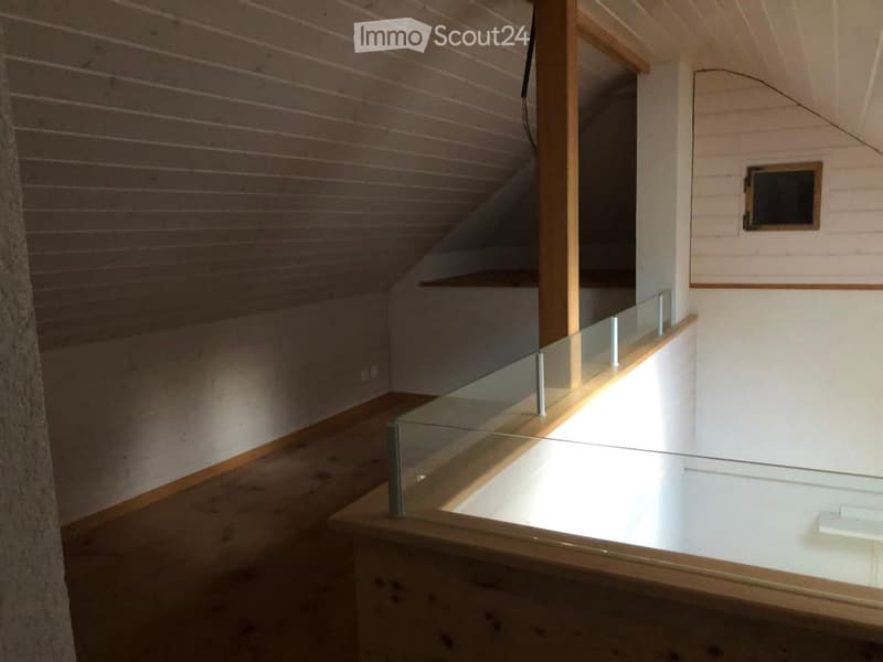 Modern hallway with wooden walls, glass railing, and exposed wooden beams on the ceiling.