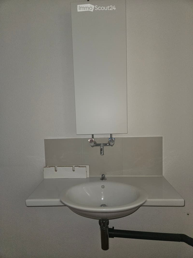 A modern bathroom sink with a sleek, minimalist design, featuring a white ceramic sink, a chrome faucet, and a large mirror above it.