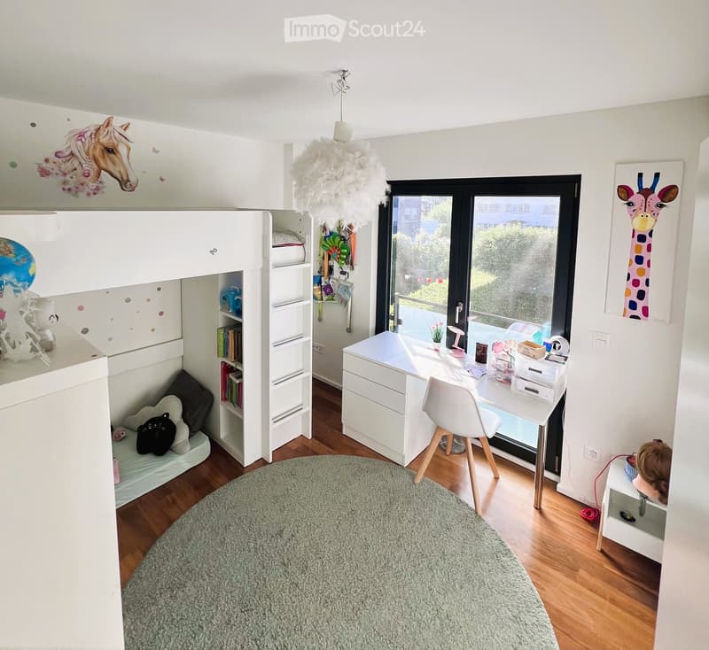 A modern, well-lit bedroom with a loft bed, desk, and various decorative items including a globe, toys, and artwork.