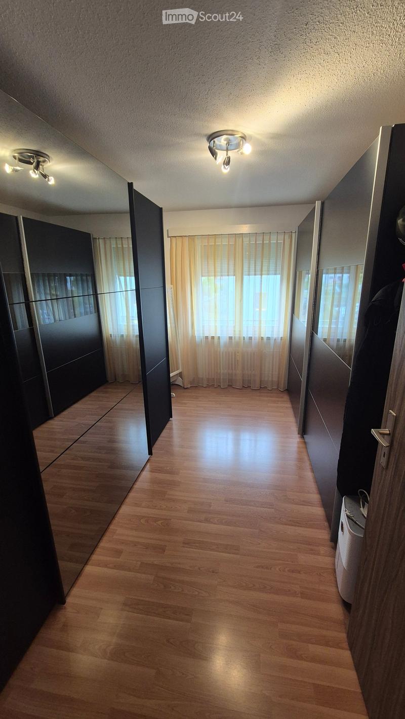Empty hallway with wooden flooring, modern lighting fixtures, and large windows with sheer curtains.