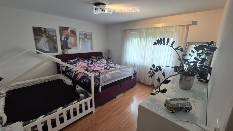 Cozy bedroom with a lofted bed, nightstand, mirror, plant, and decorative picture frames on the wall.