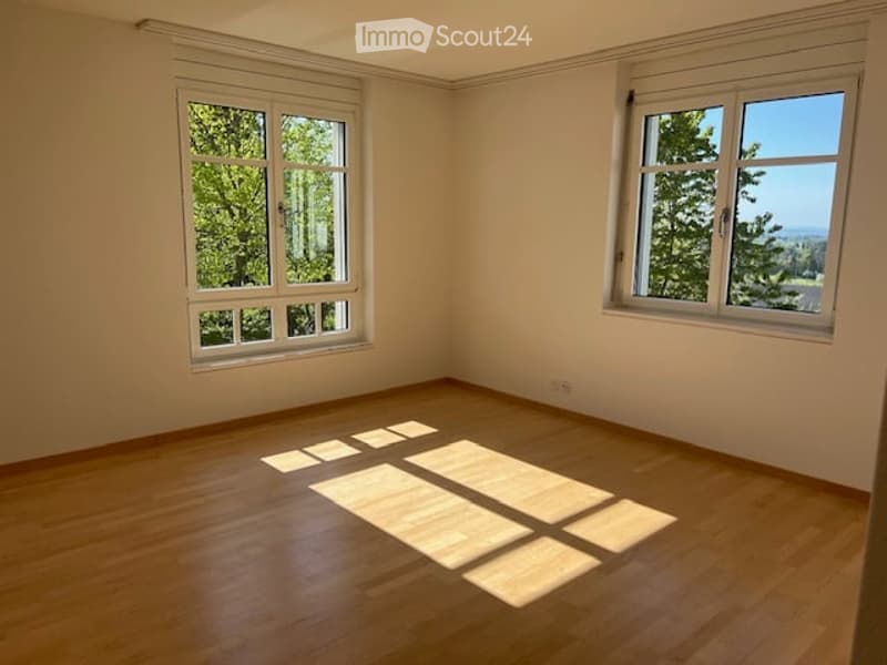 Empty room with wooden flooring and large windows allowing natural light to enter. No furniture or equipment present.