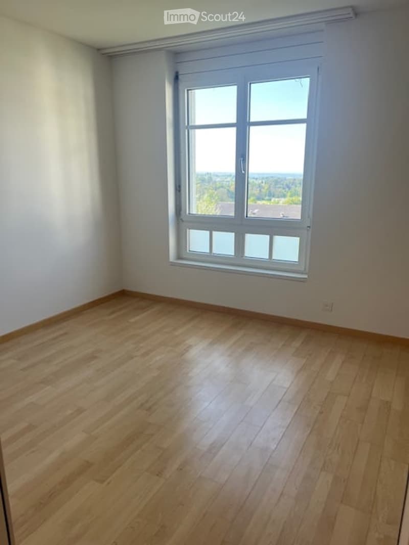 Empty room with wooden flooring and large window, no furniture or equipment.
