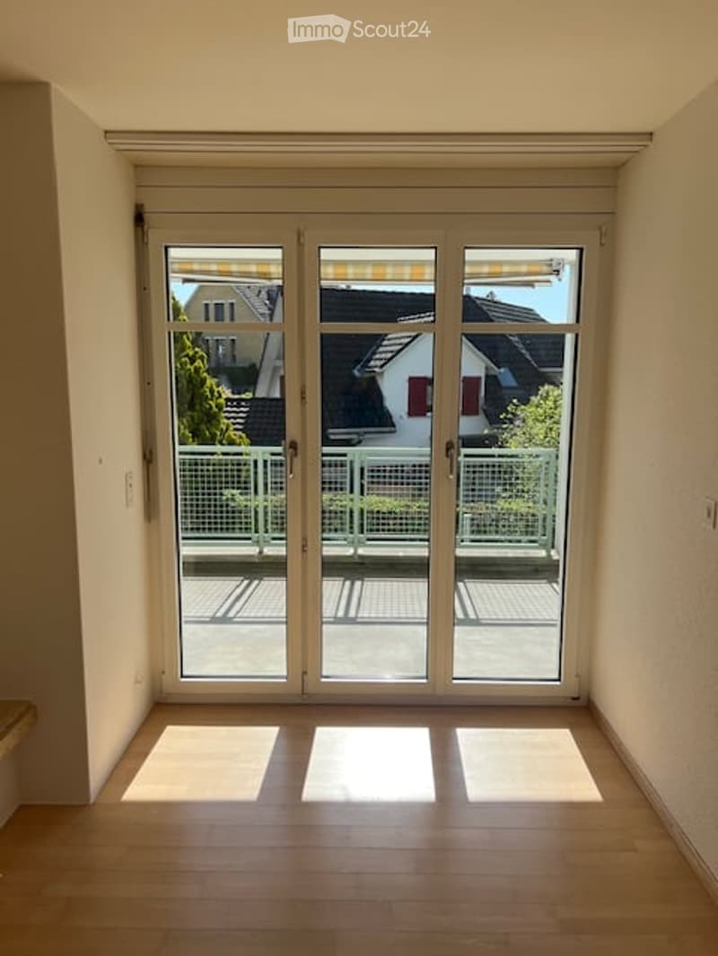 Empty room with large sliding glass doors leading to a balcony, wooden flooring, and natural light.