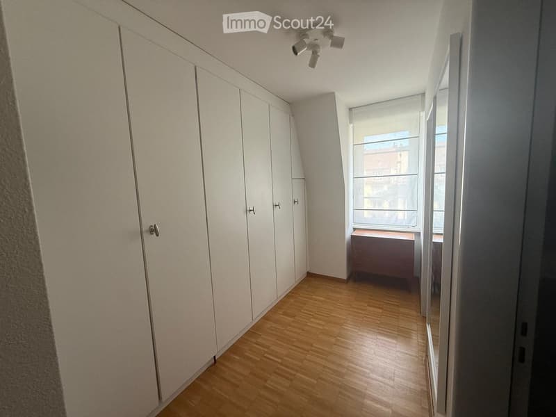 Empty room with wooden flooring, white built-in wardrobes, and a window with blinds. No furniture or personal items are present.