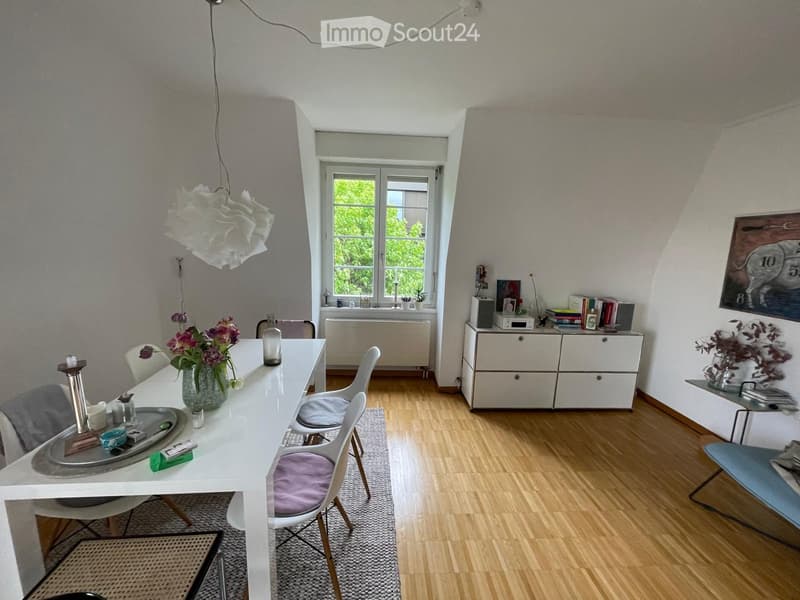 Bright dining area with white dining table, chairs, cabinet, and decorative items.