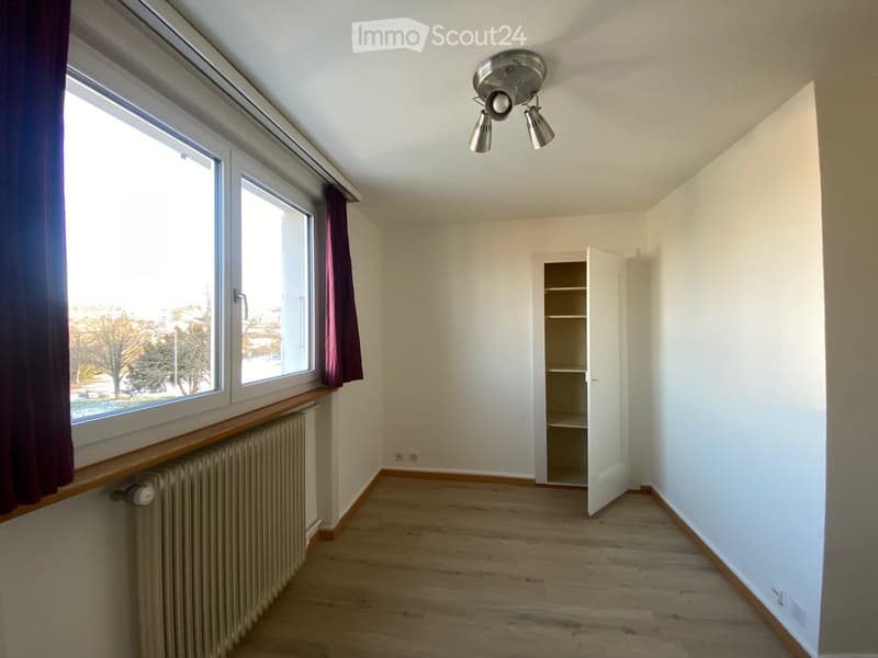 large window, open door to closet, radiator, wooden floor, lights on ceiling