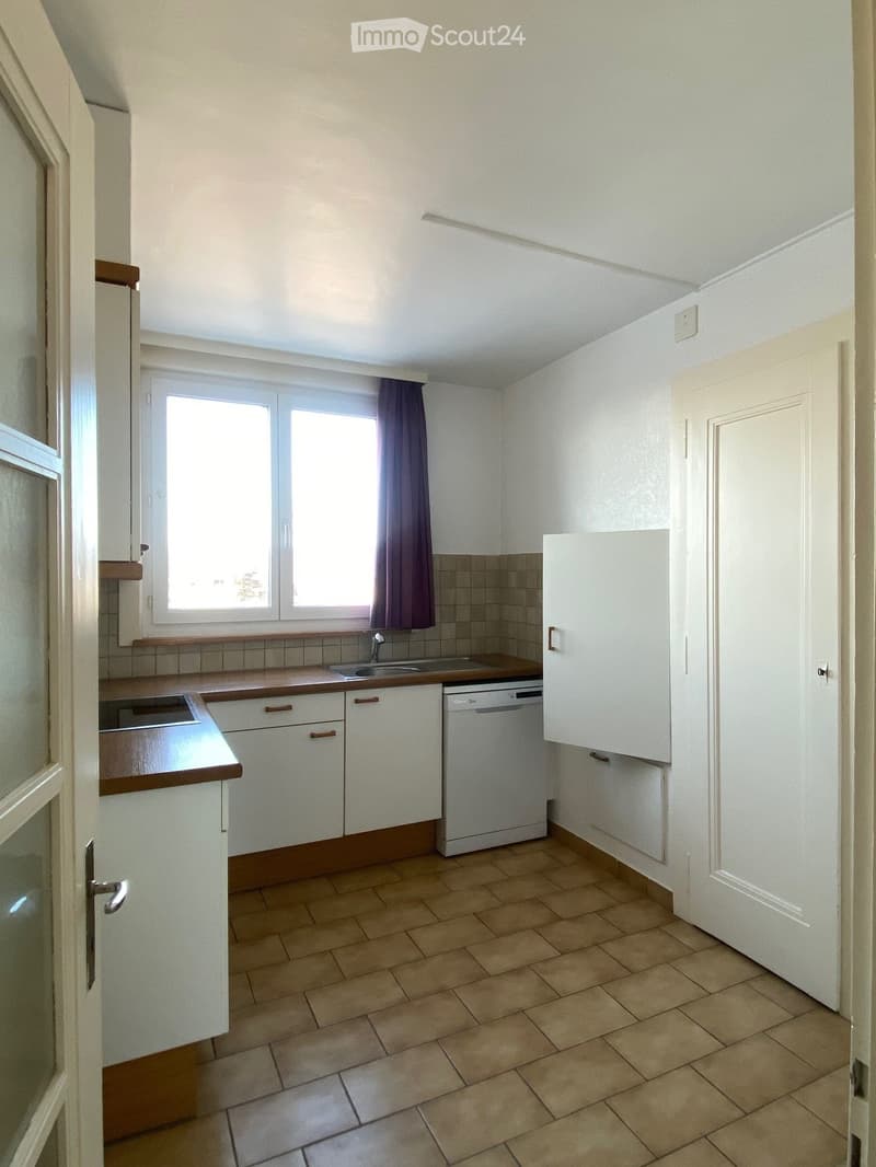 clean, simple kitchen with white cabinets, brown countertops, tile flooring, dishwasher, sink, window, and curtains