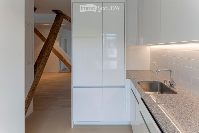 modern kitchen with white cabinets, granite countertop, stainless steel sink, wooden beams