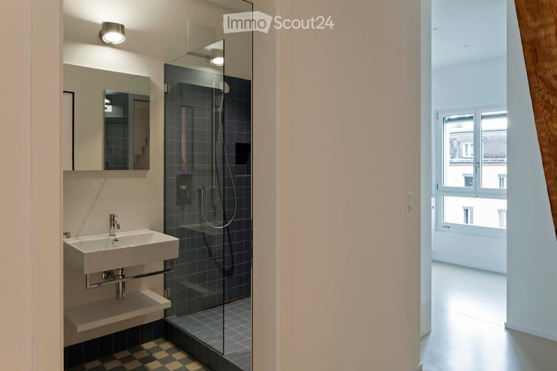 Bathroom with glass shower, white sink, mirror, blue tiles, white walls, checkered floor, window with view