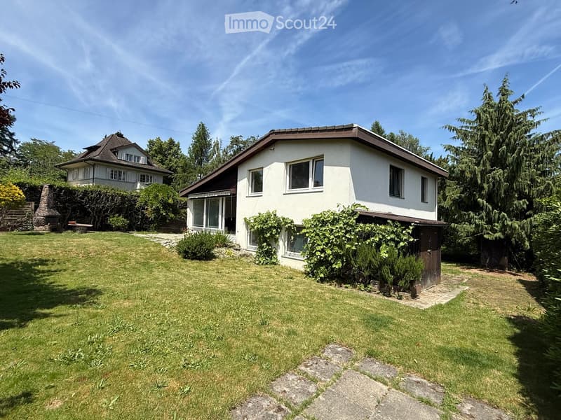 Two-story house with white walls, multiple windows, and a well-maintained lawn in front.