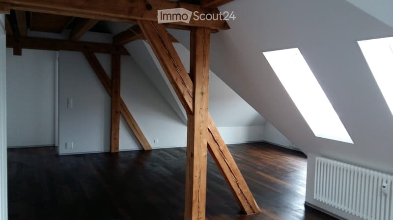 Unfurnished Room. Empty attic space with wooden beams, wooden flooring, and skylight windows.