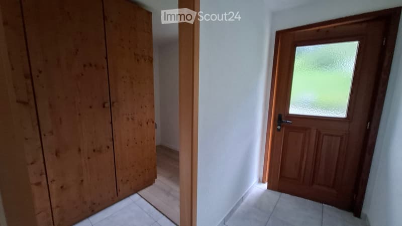 Empty hallway with white tiled floor, white walls, and two wooden doors, one with a frosted glass panel.