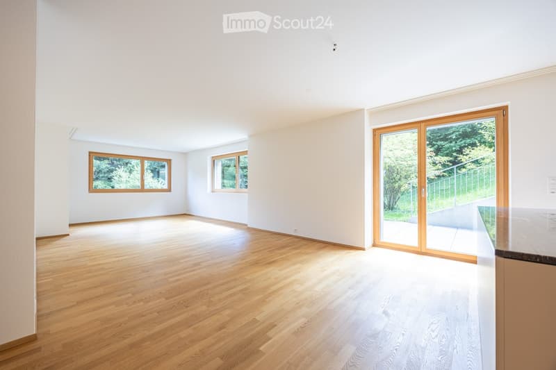 Bright, empty room with wooden flooring, white walls, large windows, and a sliding glass door leading to an outdoor area.