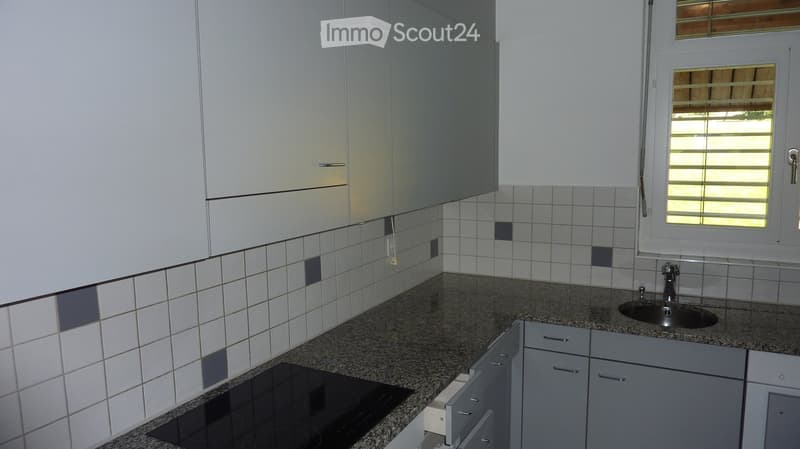 Modern kitchen with white cabinets, granite countertop, electric stove, and sink.