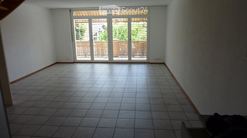 Empty room with tiled floor and large sliding glass doors leading to an outdoor area.