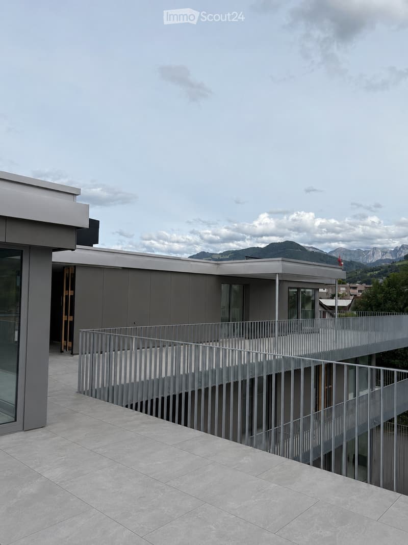 Modern balcony with grey metal railing, tiled floor, and scenic mountain view in the background.