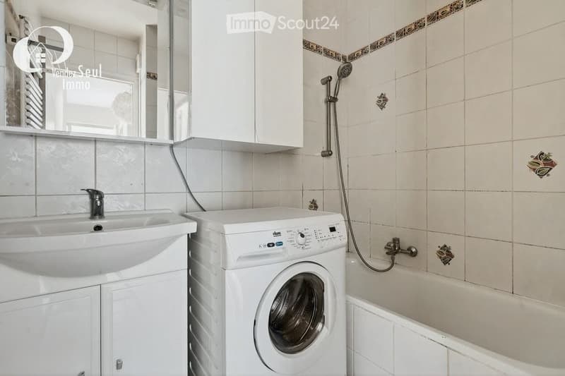 Bathroom with a white sink, mirror, bathtub, shower, and a washing machine.