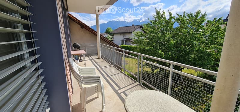 Balcony with a view of mountains, featuring a table and chairs, a grill, and a railing.