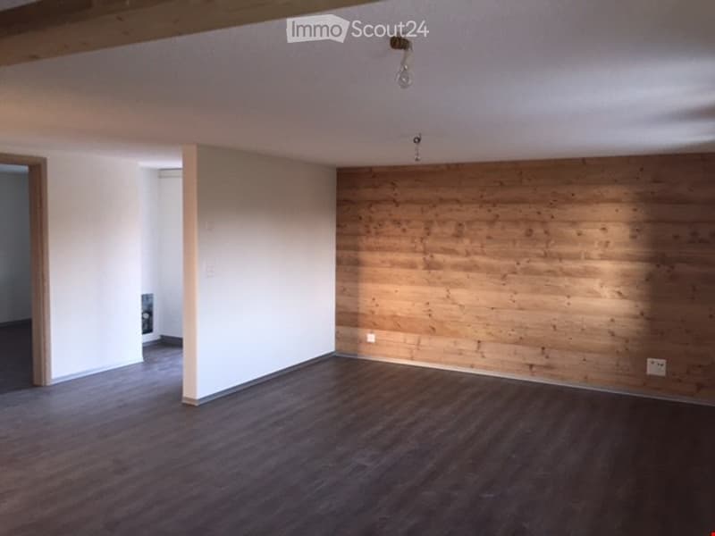 Empty room with wooden flooring, white walls, and a wooden accent wall. No furniture or equipment present.