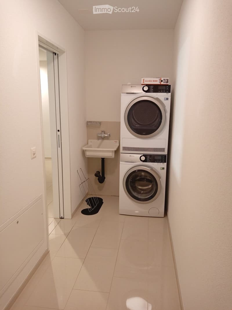 white tiled floor, white walls, washing machine, dryer, sink, cabinet