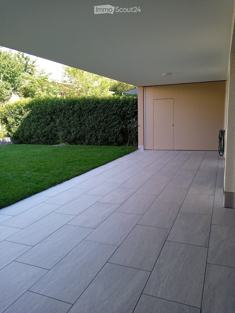 tiled floor, large green lawn, hedge, building with door